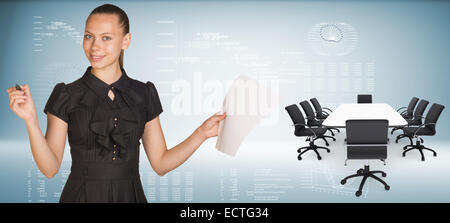 Beautiful businesswoman holding blank paper sheet and felt pen ready to use.  Beside is big conference table with chairs Stock Photo