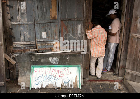 Mauritius, Mahebourg, men in doorway of shoe repair and upholsterer’s shop Stock Photo