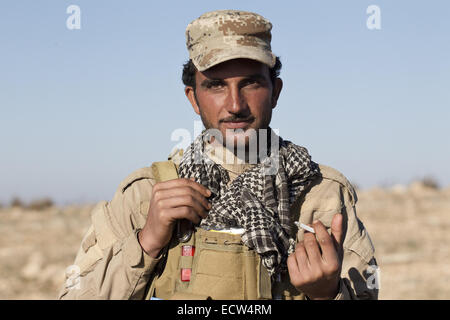 Dec. 11, 2014 - Sinjar Mountains, Iraqi-Kurdistan, Iraq - 11/12/2014. Sinjar Mountains, Iraq. A Yazidi fighter smokes a cigarette as he waits for Iraqi Air Force helicopters to bring supplies and evacuate some of the refugees on the top of Mount Sinjar.Although a well publicised exodus of Yazidi refugees took place from Mount Sinjar in August 2014 many still remain on top of the 75 km long ridge-line, with estimates varying from 2000-8000 people, after a corridor kept open by Syrian-Kurdish YPG fighters collapsed during an Islamic State offensive. The mountain is now surrounded on all sides Stock Photo