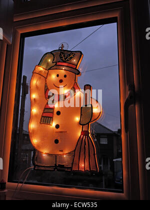An electric snowman on a window, lit up for Christmas