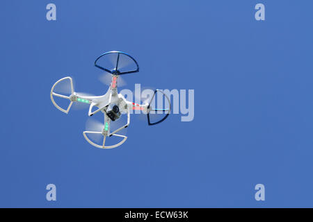 Quadcopter. Quadracopter. Drone. With video camera attached. View from under side during flight. Against blue sky. Stock Photo