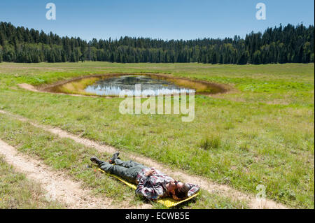 Male Caucasian hiker in his 40s takes a nap in the Kaibab Plateau area on the Arizona Trail near a water tank, AZ, US Stock Photo