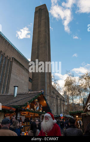 Santa Claus /  Father Christmas walking through the Christmas market in front of the Tate Modern art gallery Stock Photo