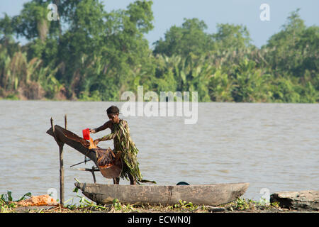 Melanesia, Papua New Guinea, Sepik River, village of Kopar. Woman in palm leaf attire along the riverfront. Stock Photo