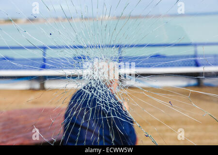 lonely old man sitting behind the window with cracked glass, conceptual image for aging process Stock Photo