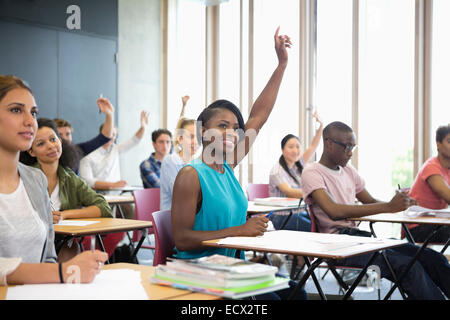 Motivated university students raising their hands at seminar Stock Photo