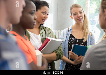 University students with books standing in corridor talking Stock Photo