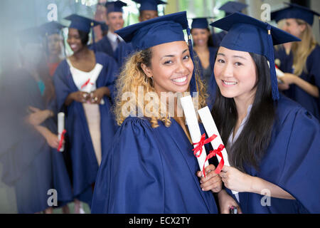 Portrait of smiling students with diplomas standing in corridor Stock Photo