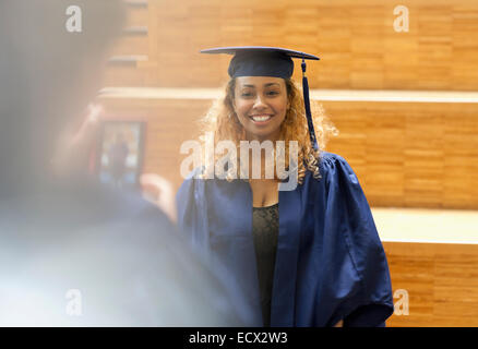 Female student in graduation gown posing for picture in university corridor Stock Photo