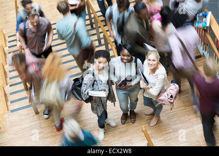 Portrait of three university students at university, other students walking down stairs Stock Photo