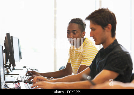 Side view of university students studying on computers in classroom Stock Photo