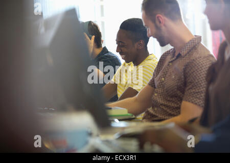 University students talking and studying on computers in classroom Stock Photo