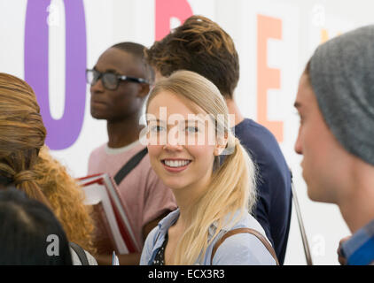 Portrait of university student standing in corridor, students talking in background Stock Photo