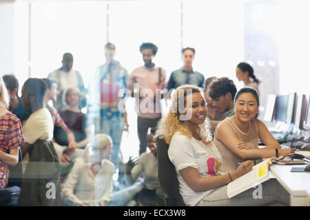 Portrait of two female university students sitting at desk in technology classroom Stock Photo