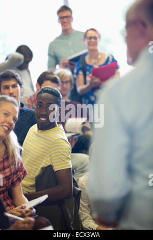 Focused students listening to professor at seminar in classroom Stock Photo