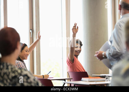 Smiling university students raising hands at seminar Stock Photo