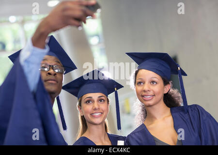 Three university students taking selfie after graduation ceremony Stock Photo