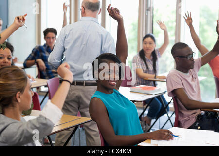 University students raising hands to answer professor Stock Photo