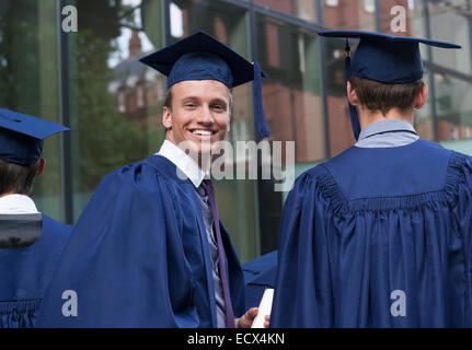 Smiling university student looking over shoulder at camera on campus Stock Photo