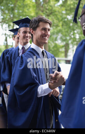 University students congratulating one another after graduation ceremony Stock Photo