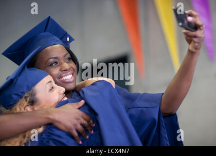 Two smiling female students taking selfie at graduation Stock Photo