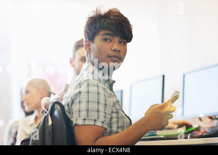 Male student sitting at desk using cell phone Stock Photo