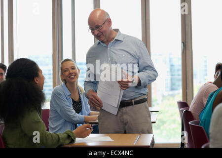 Teacher talking with students during lecture in sunlit classroom Stock Photo