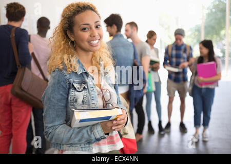 Smiling female student holding books and looking at camera Stock Photo