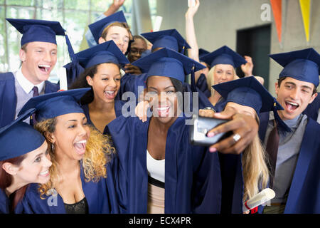 Group of smiling students in graduation gowns taking selfie on graduation day Stock Photo