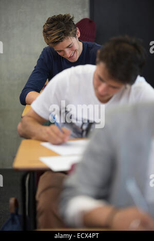 View of smiling students sitting at desks during an exam in classroom Stock Photo