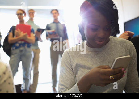 Portrait of smiling female student looking at smart phone with other students in background Stock Photo
