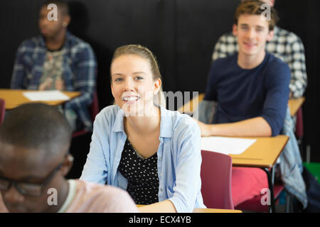 View of smiling students sitting at desks in classroom Stock Photo