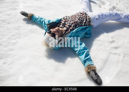 Happy woman making snow angels Stock Photo