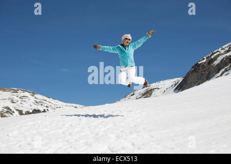 Exuberant woman jumping in snow Stock Photo