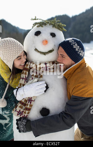 Couple hugging snowman Stock Photo