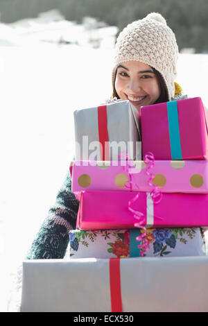 Portrait of smiling woman carrying stack of gifts Stock Photo
