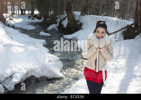 Portrait of smiling woman walking along snowy riverbank Stock Photo