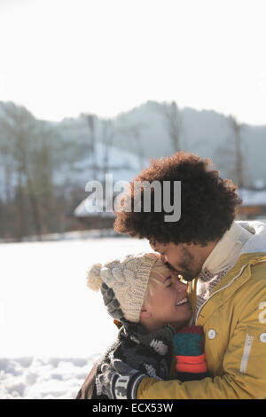 Man kissing woman's forehead in snow Stock Photo