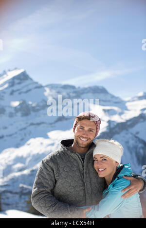 Portrait of smiling couple hugging below mountain Stock Photo