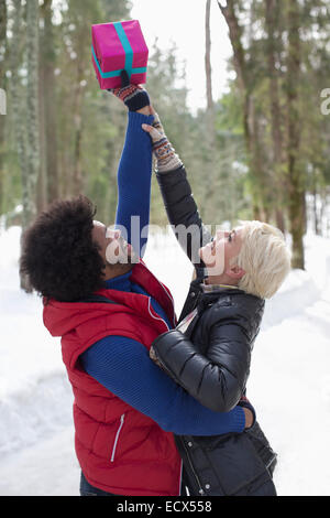 Couple reaching for Christmas gift in snow Stock Photo