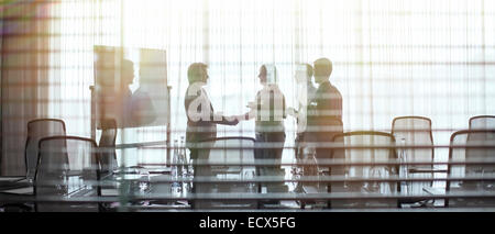 Business people standing in conference room shaking hands Stock Photo