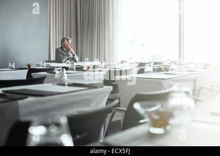 Mature businessman sitting in office restaurant with hands clasped Stock Photo