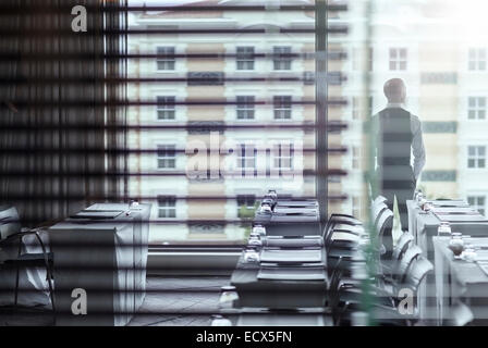 Young businessman standing in conference room looking out of window Stock Photo