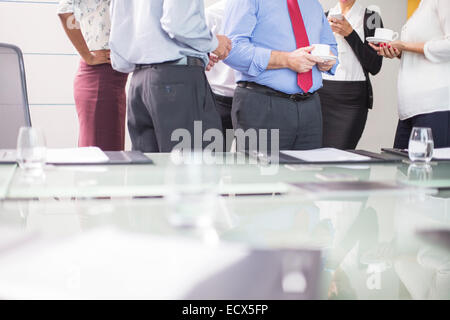 Business people standing in conference room with coffee cups in hands Stock Photo