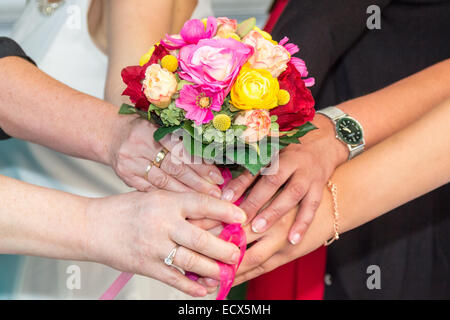 Many hands hold a bridal bouquet together Stock Photo