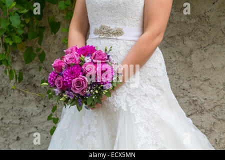 A beautiful bride holding her purple bouquet of flowers Stock Photo