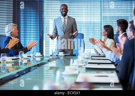 Businessman giving speech in conference room, colleagues clapping hands Stock Photo