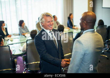 Smiling businessmen shaking hands during meeting in conference room Stock Photo