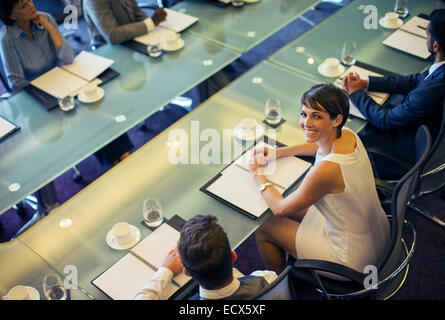 High angle view of smiling businesswoman looking at camera and sitting in conference room Stock Photo