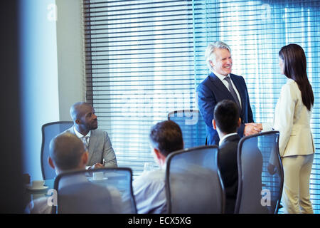 Businessman shaking hands with businesswoman in conference room Stock Photo